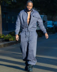 Combinaison homme oversize grise James Suit boutonnée, cordon à la taille, jambes resserrées à la cheville, portée avec des bottes noires