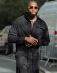 Combinaison homme oversize noire James Suit, col chemise et poche poitrine à rabat, portée par un mannequin de 1,80 m en taille XL – vue 1